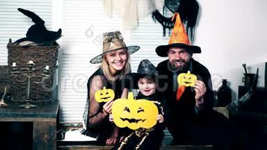 父亲、母亲和他们的儿子穿着女巫、女巫和骷髅的衣服，手里拿着甜瓜庆祝